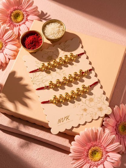 NVR Set of 3 Gold Toned Ghungroo & Red Thread Rakhi With Roli Chawal Chandan Mishri